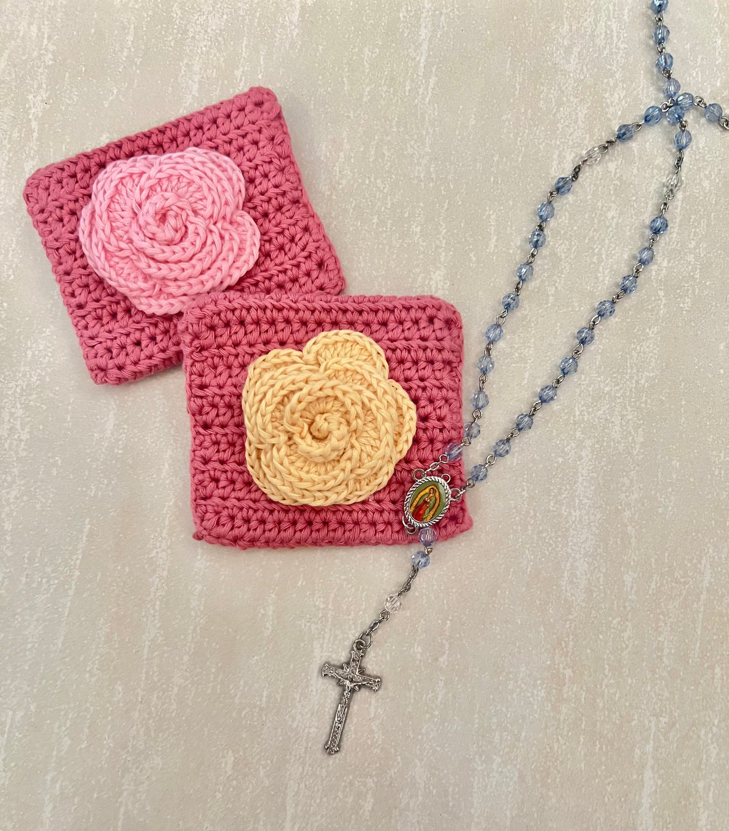 A rosary of Our Lady of Guadalupe with a pink crochet pouch and yellow flower design.