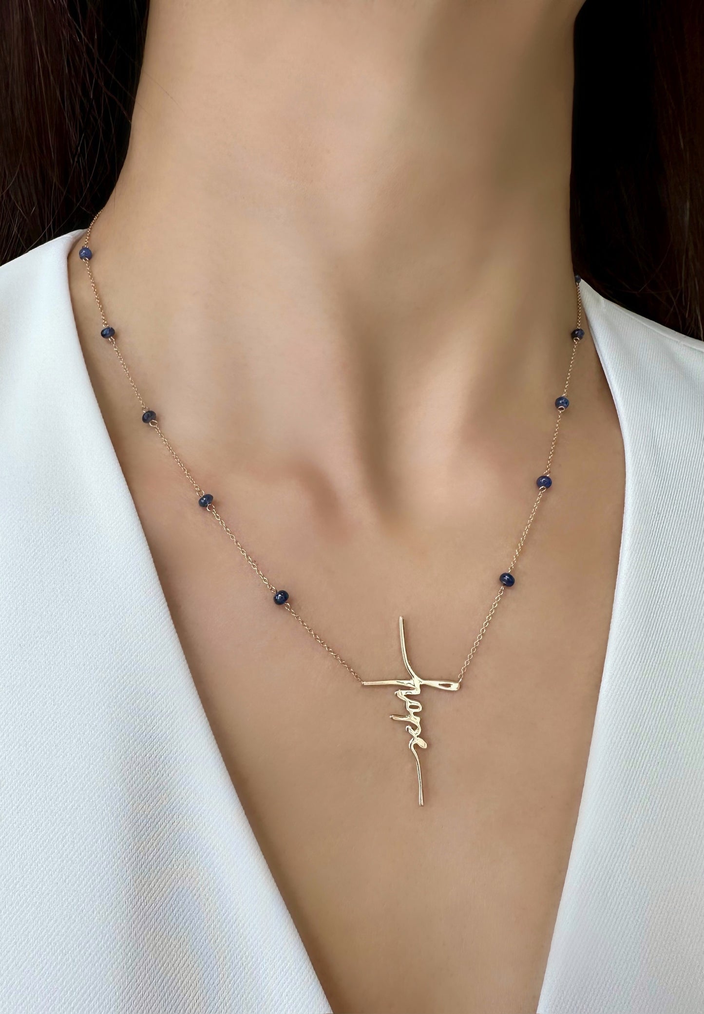 A Hope Necklace with 14K yellow gold and blue sapphires, shown on a model.