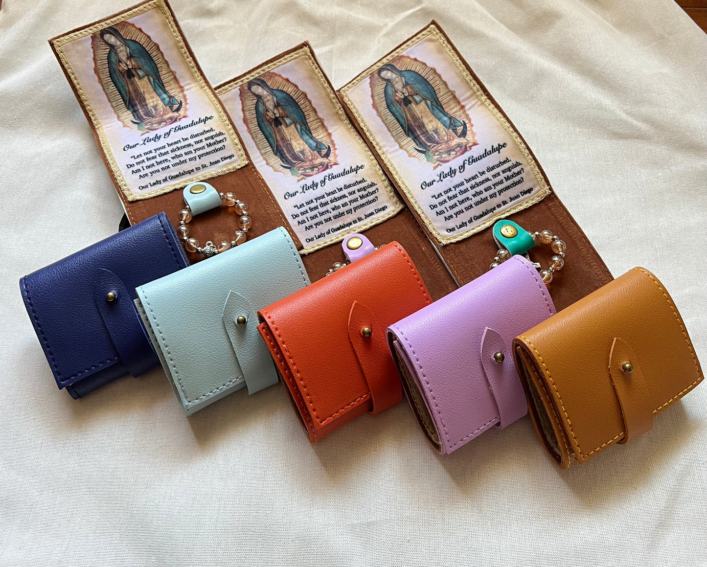 Set of colorful leather wallets, attached with the feature Our Lady of Guadalupe and with rosary.