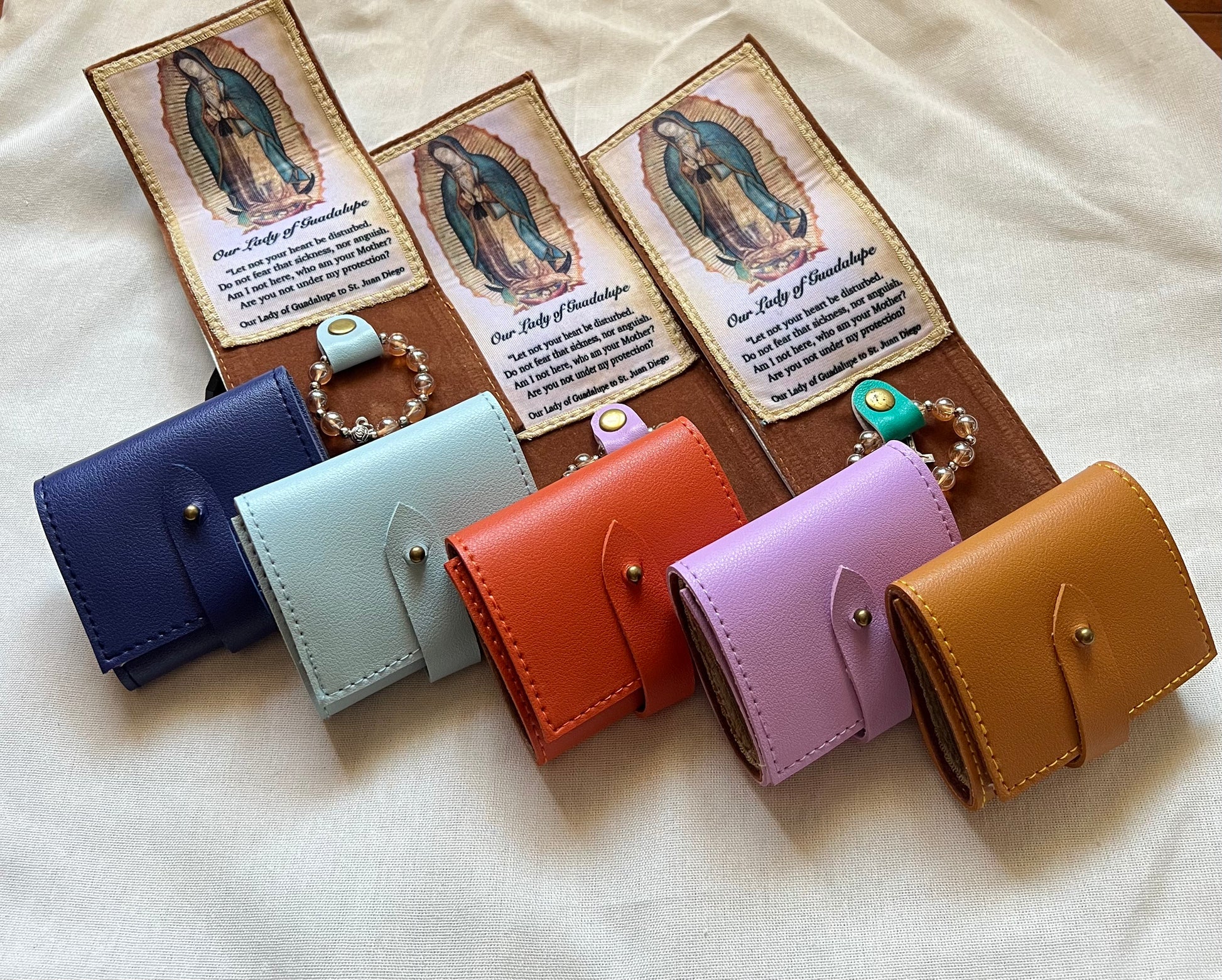 Set of colorful leather wallets, attached with the feature Our Lady of Guadalupe and with rosary.