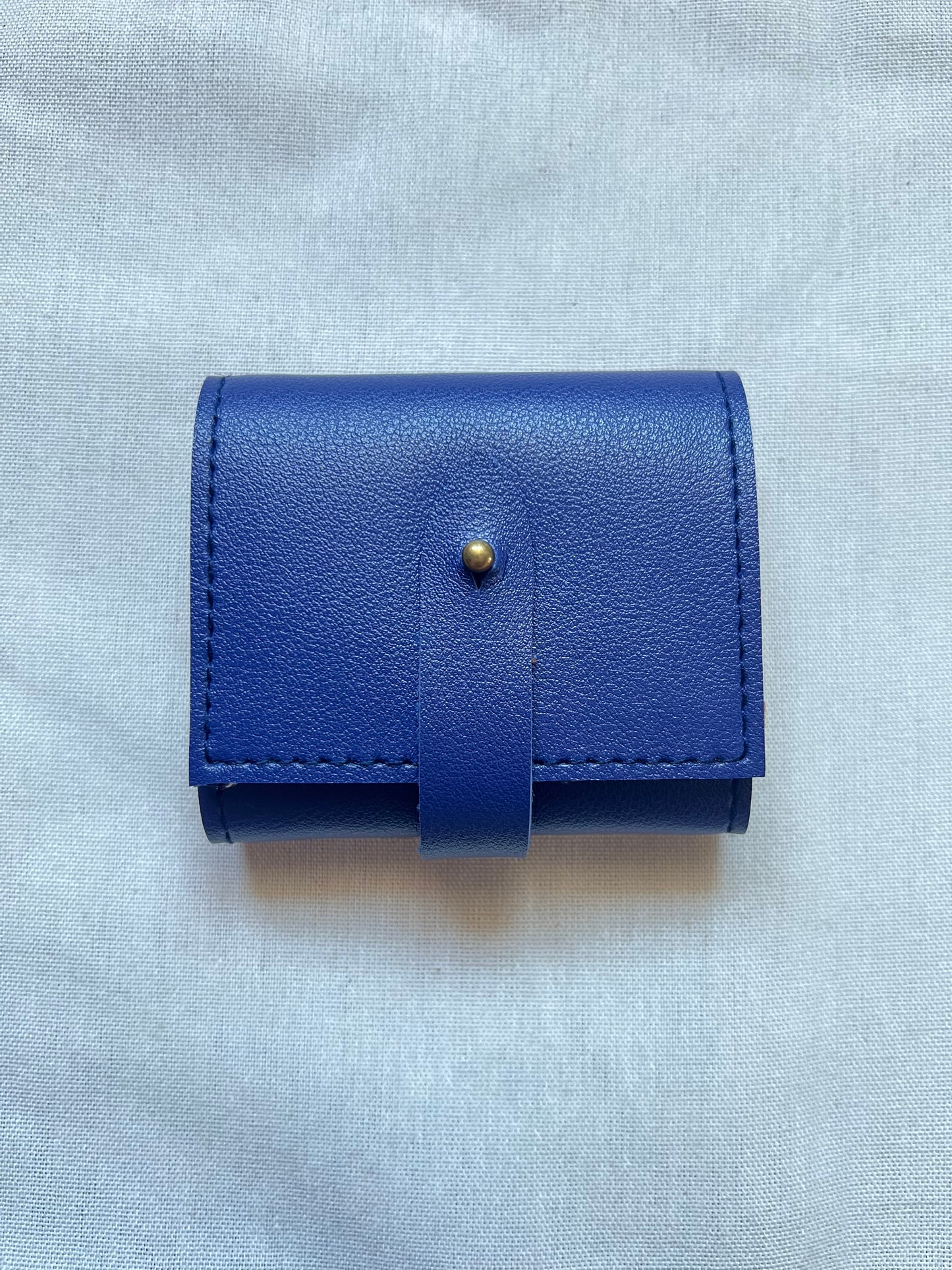 Blue leather wallet with a button on a light gray background