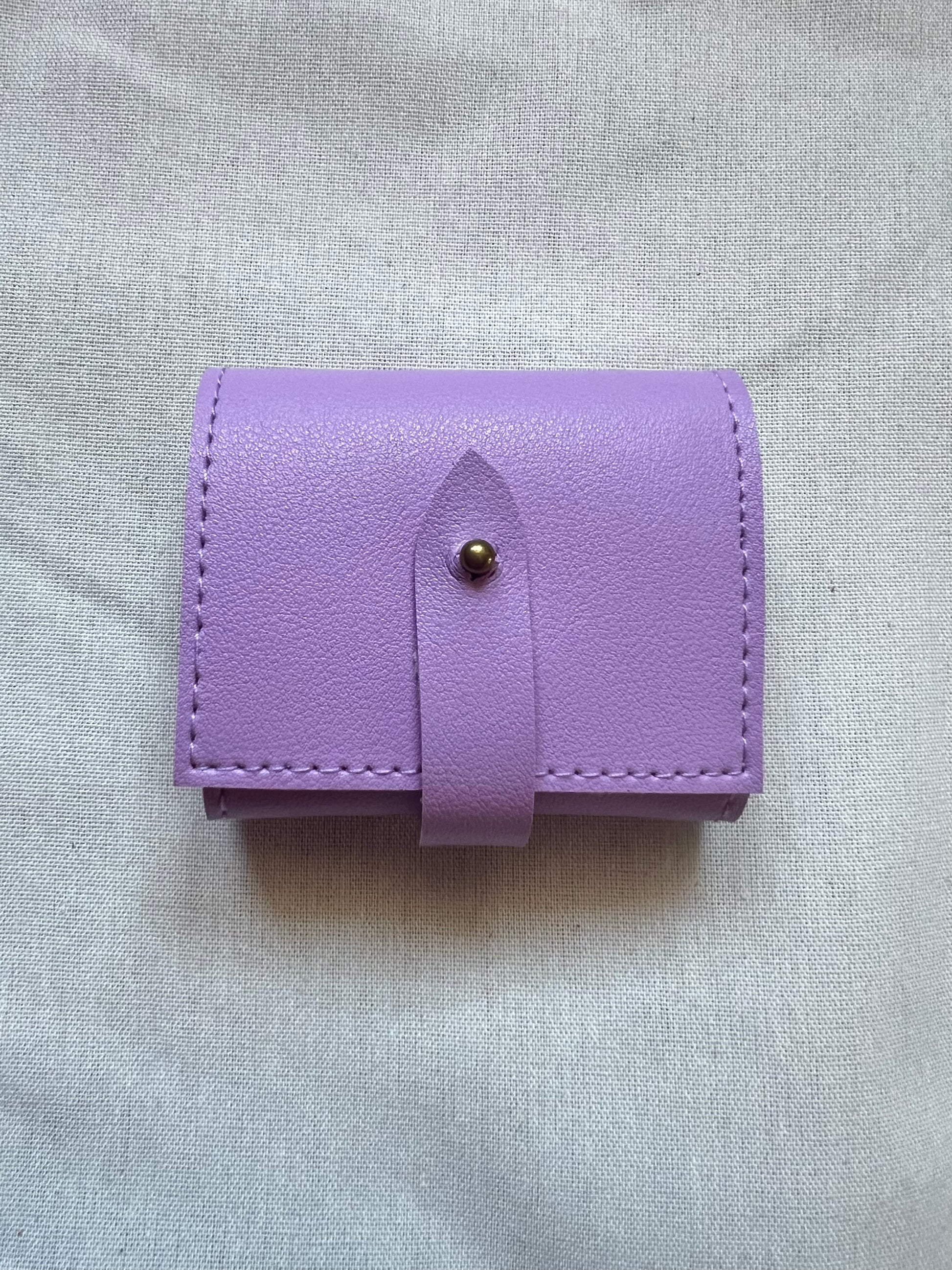 Purple leather wallet with a button on a light gray fabric background