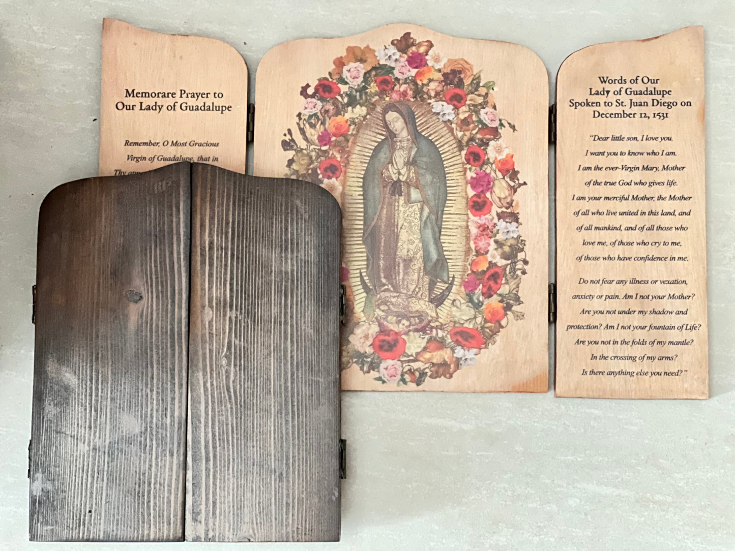 A wooden triptych featuring an image of Our Lady  of Guadalupe with floral designs, with inscriptions on the shutters. The left shutter is inscribed with a prayer, while the right shutter has the words of Our Lady to St. Juan Diego. Together with the example of how it will look like when it is close.