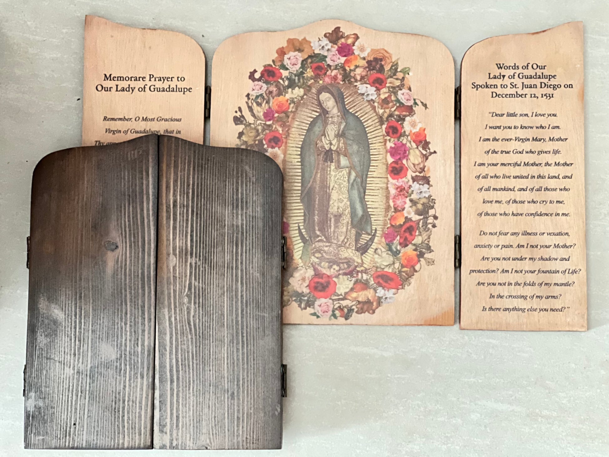 A wooden triptych featuring an image of Our Lady  of Guadalupe with floral designs, with inscriptions on the shutters. The left shutter is inscribed with a prayer, while the right shutter has the words of Our Lady to St. Juan Diego. Together with the example of how it will look like when it is close.