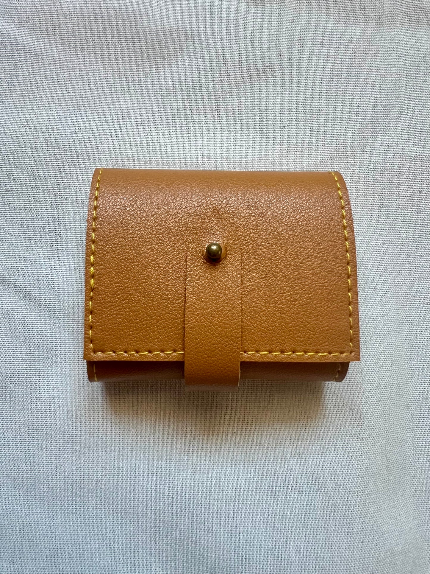 Brown leather wallet with a strap on a light gray background
