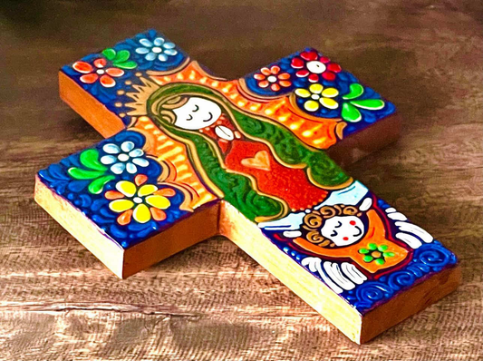Hand-painted wooden cross with the image of Our Lady on it, displayed on a wooden surface.