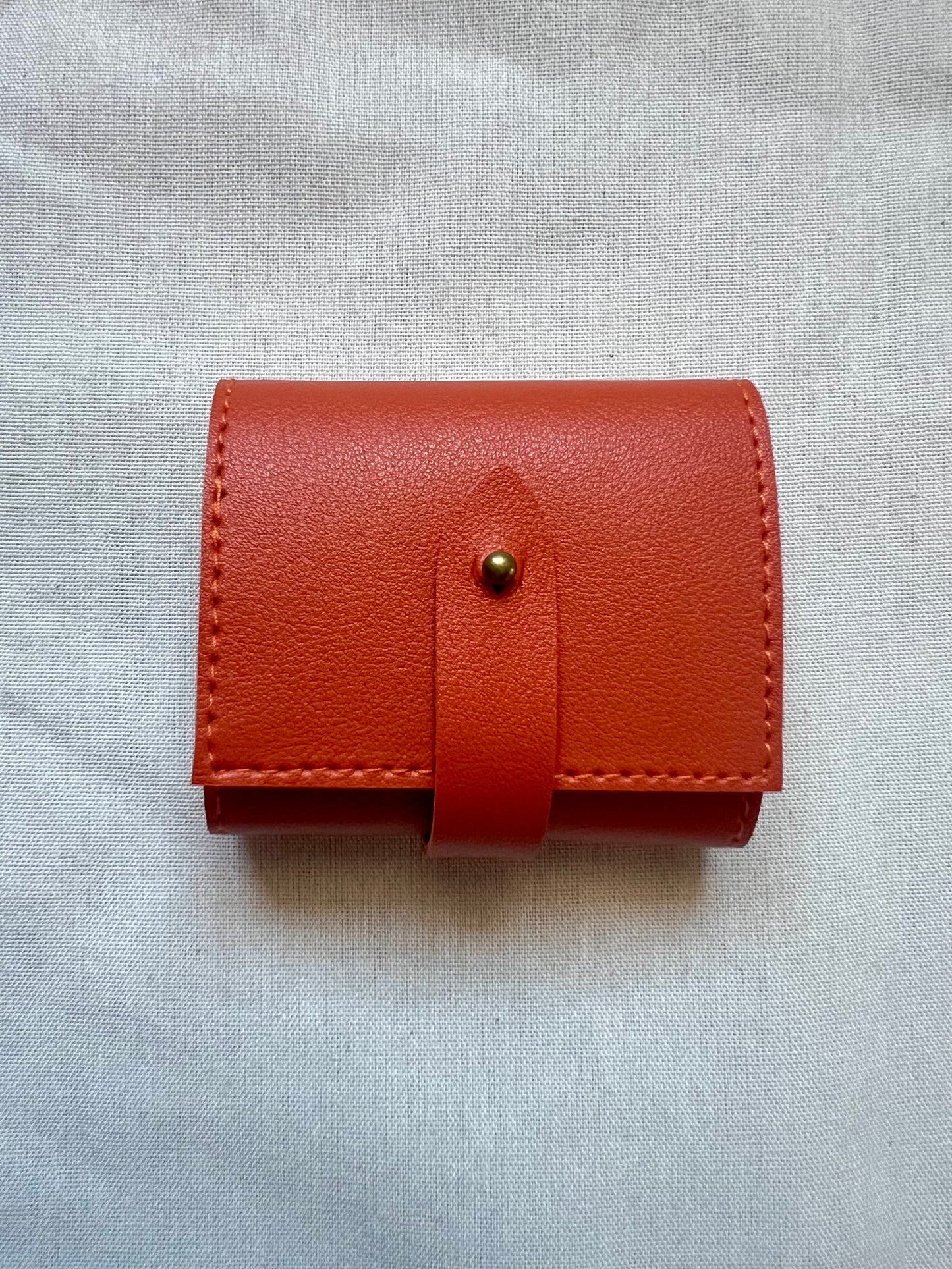 Brown leather wallet with a button on a light gray background