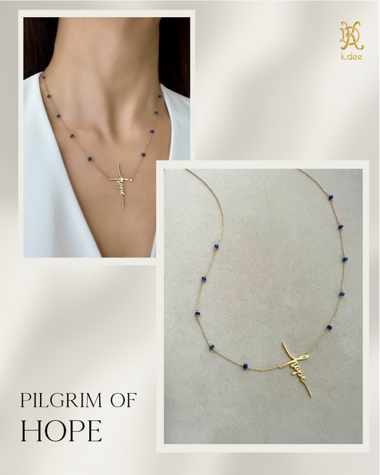 A Hope Necklace with 14K yellow gold and blue sapphires, shown on a model and on a display card with the brand name 'Pilgrim of Hope'.
