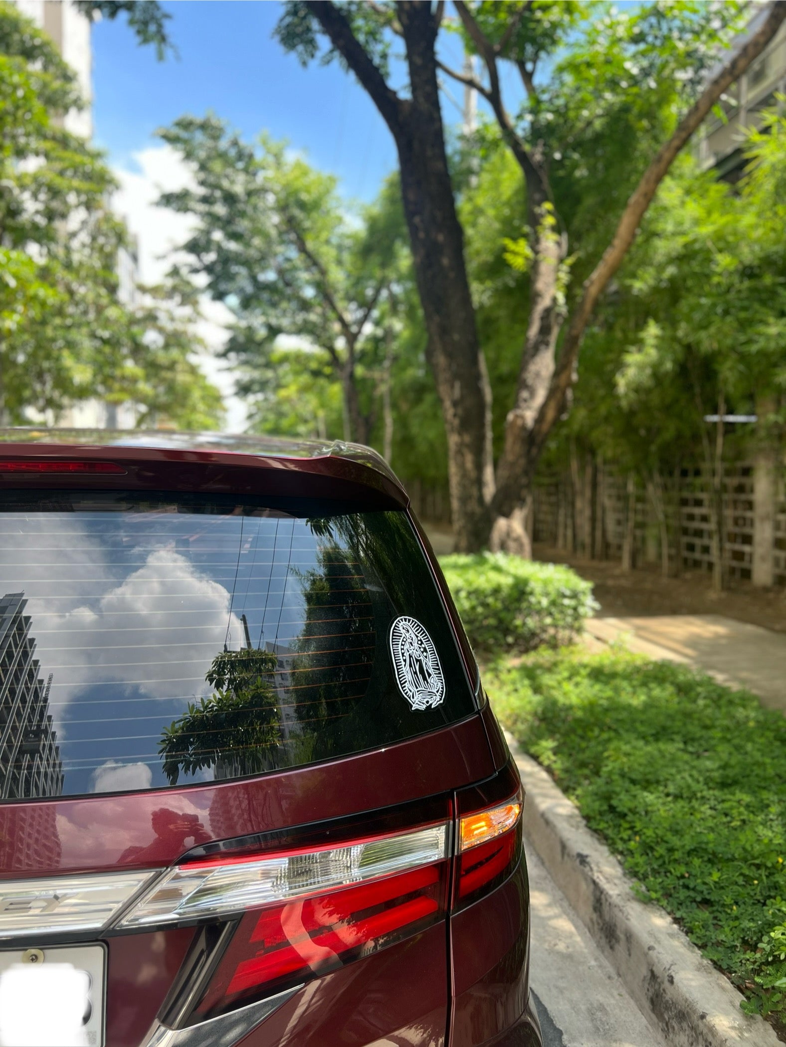 A sticker of the Virgin Mary in a white and transparent color, attached at the back of car. 