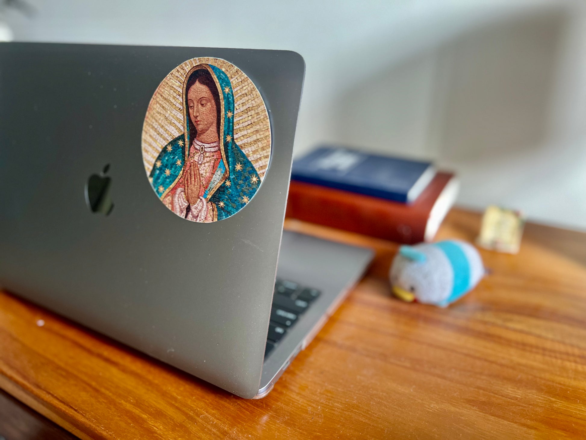 A round sticker of Virgin Mary attached at the side back of MacBook. 